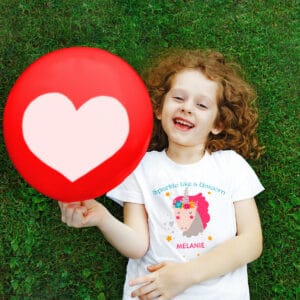 Child laying in the grass wearing a shirt that reads "Sparkle like a Unicorn"